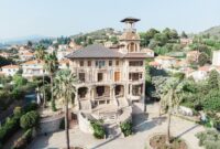 Villa Liberty architecture Picturesque scenery of aged Baroque styled Villa Grock and Museo del Clown located in hilly terrain near typical residential houses against cloudless blue sky in Italy